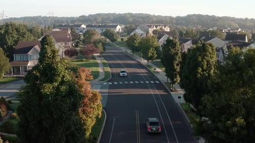 Aerial of traffic driving through residential suburban community in USA. Lifestyle establishing shot