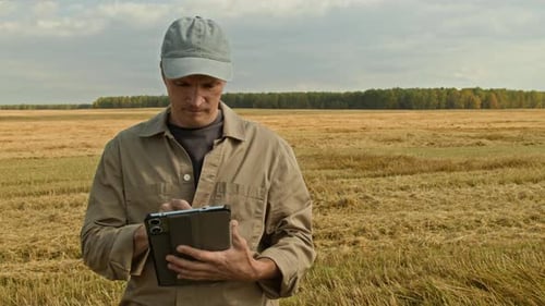 Farmer using Tablet in Wheat Field and Looking at Camera