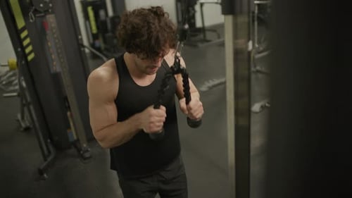 Muscular Man Performing Triceps Pushdowns on Cable Machine in Gym