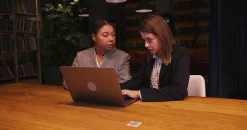 Two Women Working Together at Laptop in Library