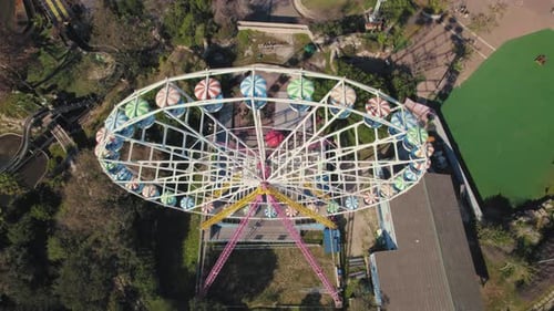 Ferris wheel spins in a small theme park - top down to pullback reveal shot