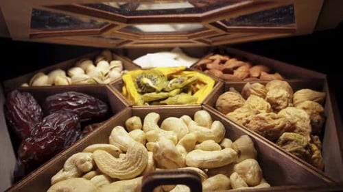 Open a wooden box with dried fruits and nuts. Close-up, in motion