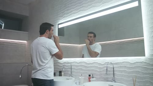 Homme heureux se brossant les dents dans la salle de bain