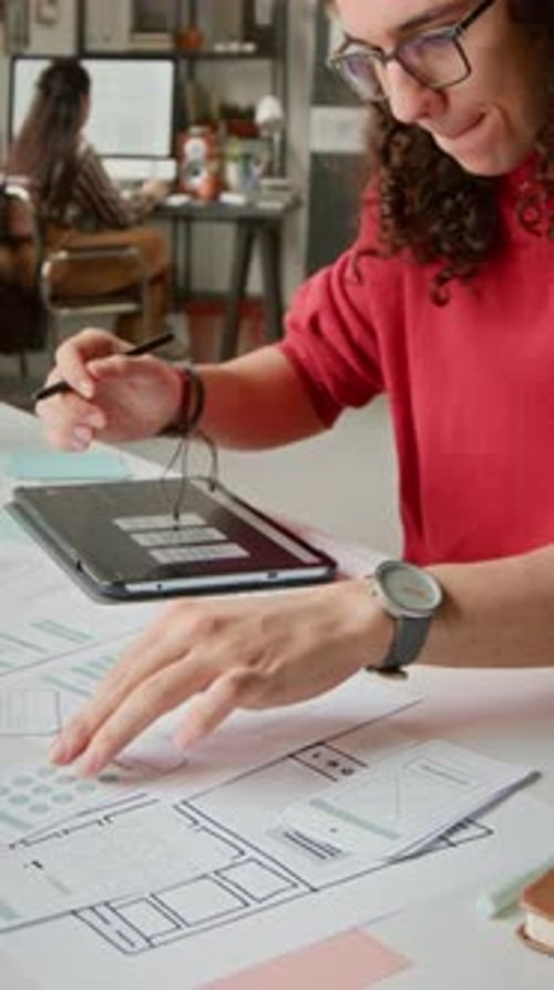 Designer Using Tablet with Wireframe Designs in Office