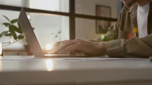 Adult Typing on Laptop in Sunny Workplace