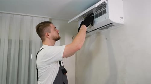 Man Installs Air Conditioner Filter in Bright Room