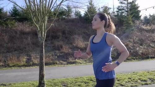 Woman Jogging on Paved Path on Sunny Day