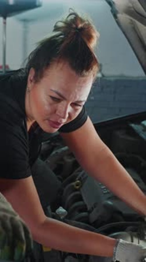 Une femme effectue l'entretien du moteur dans un garage pendant la journée