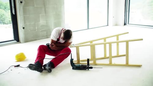 Injured Construction Worker Sitting on Floor After Accident