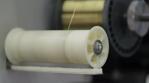 Close Up of Plastic Spool with Thin Industrial Wire on Production Machine