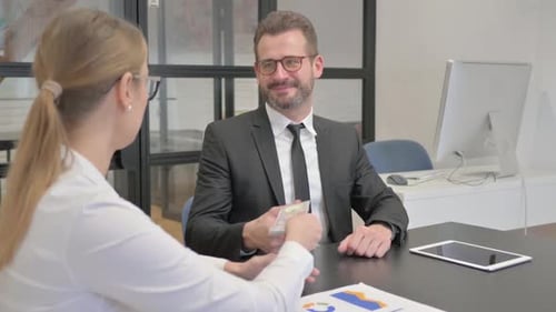 Businessman Giving Money to Woman in Office