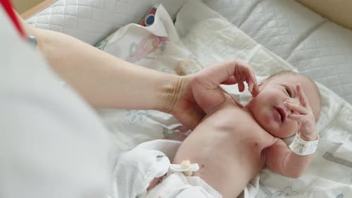 Caregiver Adjusts Newborn in Hospital Crib
