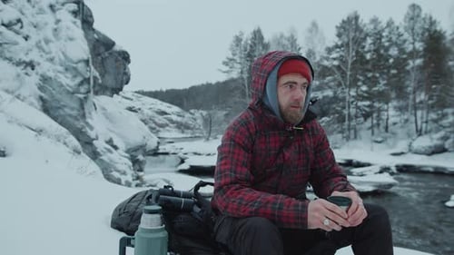 Man Drinking from Mug in Snowy Winter Landscape
