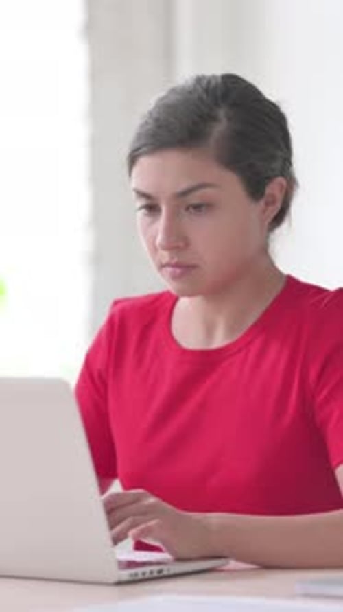Indische Frau reagiert auf Verlust, während sie einen Laptop benutzt, vertikales Video