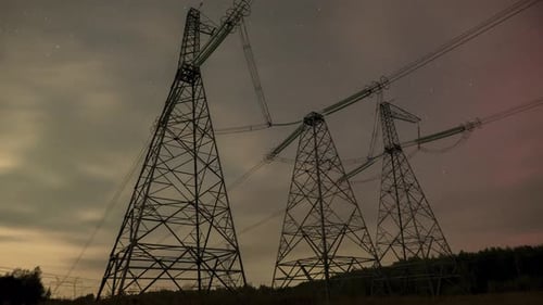 Starry Sky with Clouds and Northern Lights Over Highvoltage Power Line Pylons