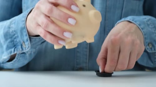 Person Open and Shaking Coins Out of Piggy Bank Closeup Woman Checking Savings