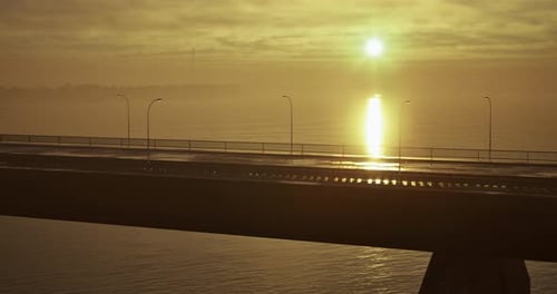 Sunrise Casts Golden Hues Over Quiet Bridge and Calm Water