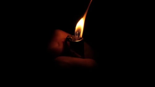 Nahaufnahme des handzündenden Feuerzeugs auf schwarzem Hintergrund, Zeitlupe