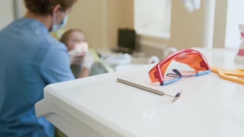 Dentist Picking Up Tools on Table
