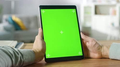 Close-up of Man Using Green Mock-up Screen Digital Tablet Computer in Portrait Mode while Sitting a