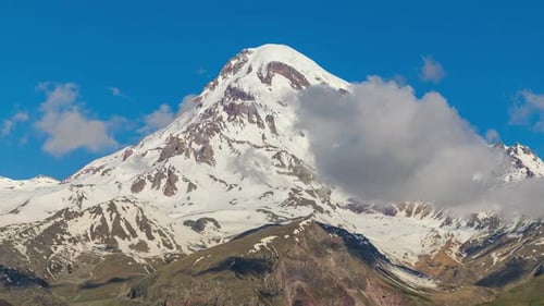 Zeitrafferaufnahme der verschneiten Bergkette unter blauem Himmel mit Dramatisch Wolken und Alpengipfeln