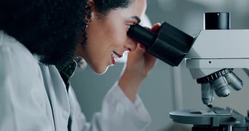 Scientist Looks Through Microscope in Bright Laboratory