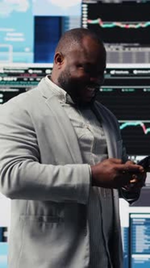 Man Smiles at his Mobile Phone in Office