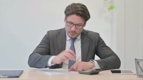 Man in Suit Calculating Business at Desk