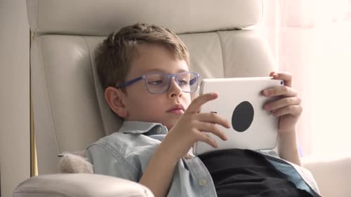 Boy in Chair Using Tablet Device Indoors