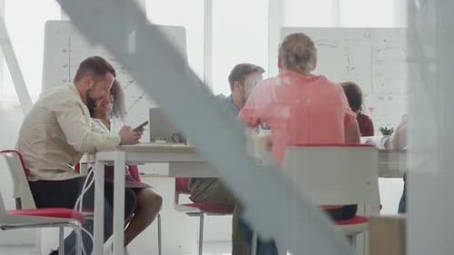Through Glass View Smiling Business People Sitting at Table in Meeting Room