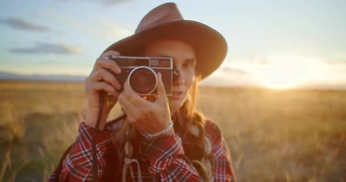 Photographer Taking Pictures with Vintage Camera in a Field at Sunset