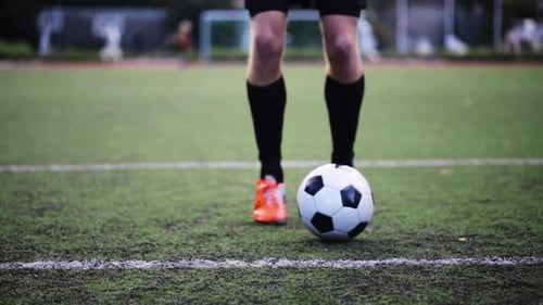 Soccer player skillfully juggling football on green field in preparation for game day