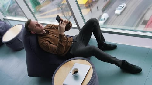 Man Relaxing in Beanbag Chair Using Phone