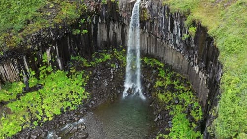 Flying Towards Small Waterfall Of Svartifoss At Vatnajökull National Park In Iceland. Aerial Drone