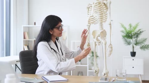 Arzt benutzt Skelettmodell während eines Videokurses auf dem Laptop