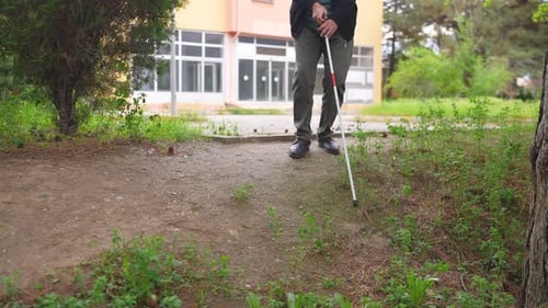 Adult Walks Outside with White Cane in Urban Area
