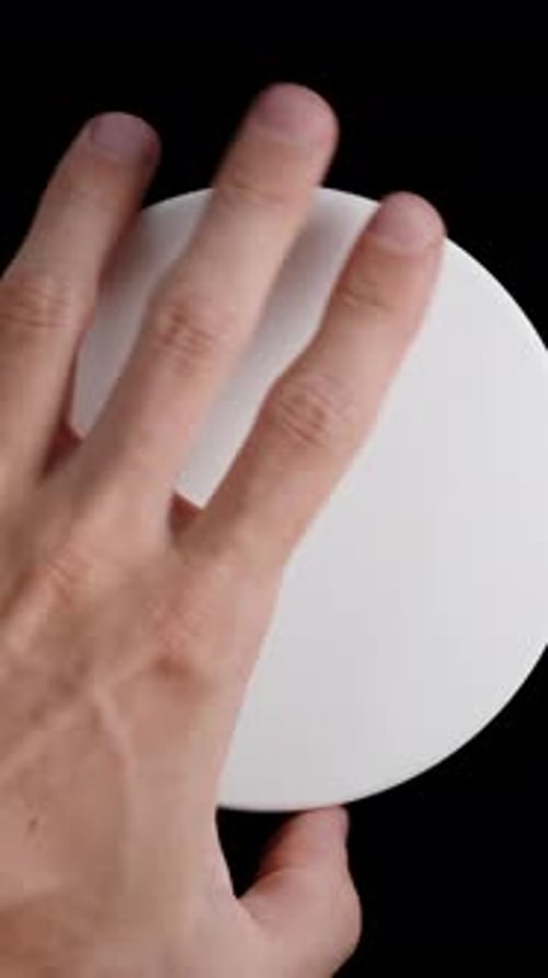 Vertical video. Top view of a white jar on a black background. I unscrew the lid and scoop