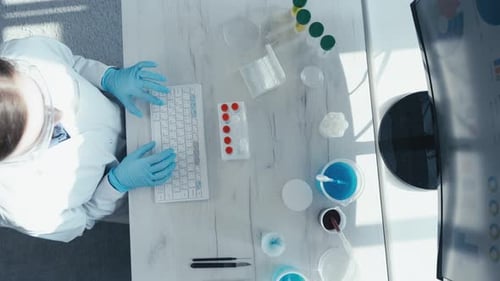 Scientist Typing at Desk with Medical Equipment