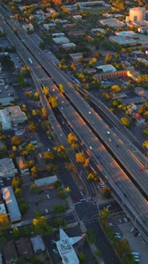 Multilane two-ways roads along the big city. Green city panorama in the rays of setting sun.