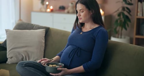 Pregnant Woman Eating Fruit on Couch Indoors