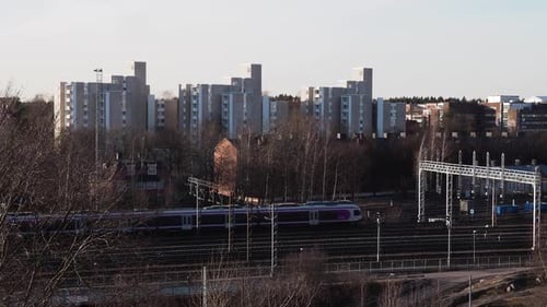 Korrigieren Sie die Drohnenaufnahme des Zuges, der auf der am weitesten entfernten Schiene von links nach rechts fährt, mit Bäumen auf beiden Seiten