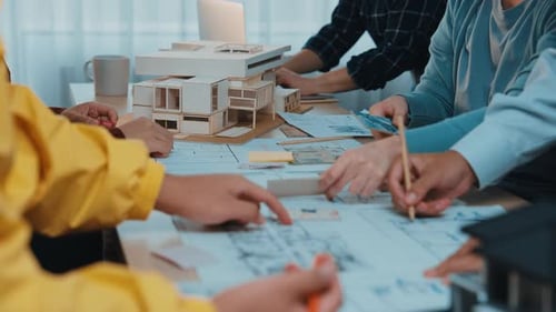 Collaborative session of architects discussing building models and floor plans in a modern office en