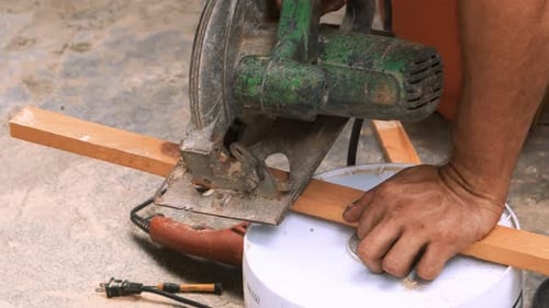 Nahaufnahme eines Zimmermanns, der mit seinem Industriekreis gekonnt einen Schnitt in ein Stück Holz ausführt