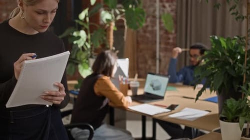 Young Female Architect with Coffee Cup Reviewing 3D Layout in Modern Office