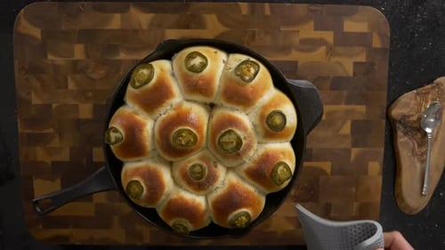 Overhead shot of fresh baked cast iron bread rolls straight out of the oven with a slow motion shot