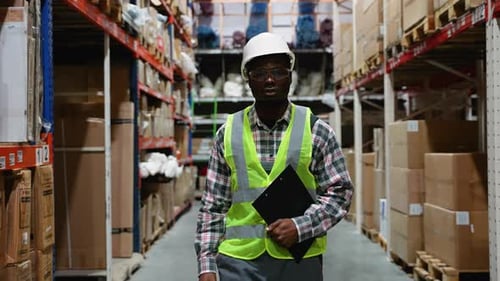 Logistics Worker Walking Through Warehouse Aisle
