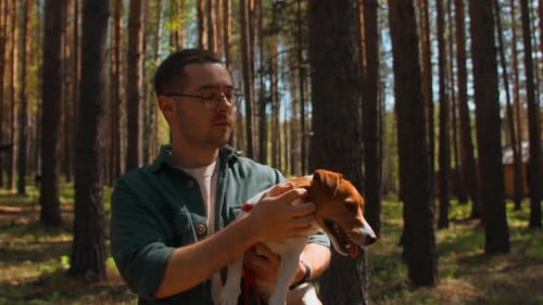 Man Holding Dog in Sunny Forest Setting