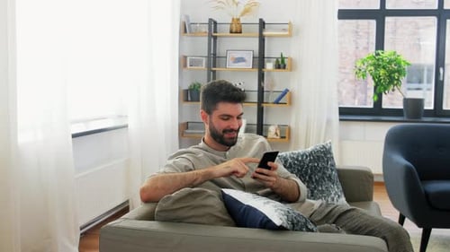 Man Relaxing on Couch Using Mobile Phone