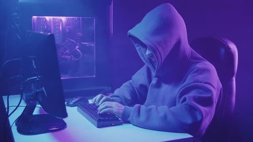 hacker in a hood works at a computer