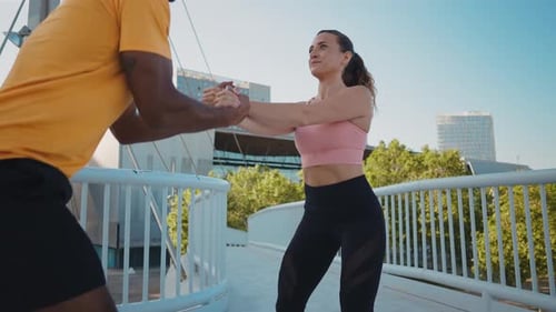 Athletic Couple Squatting Together on Urban Bridge
